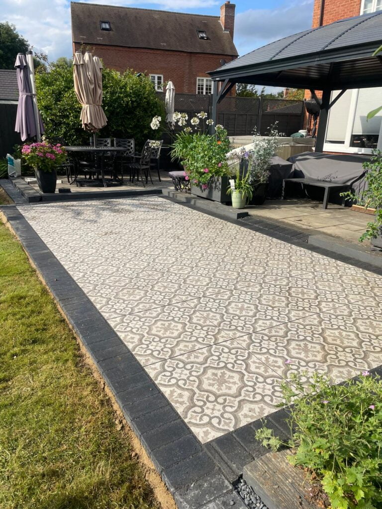 Garden patio with patterned tiles and seating area.