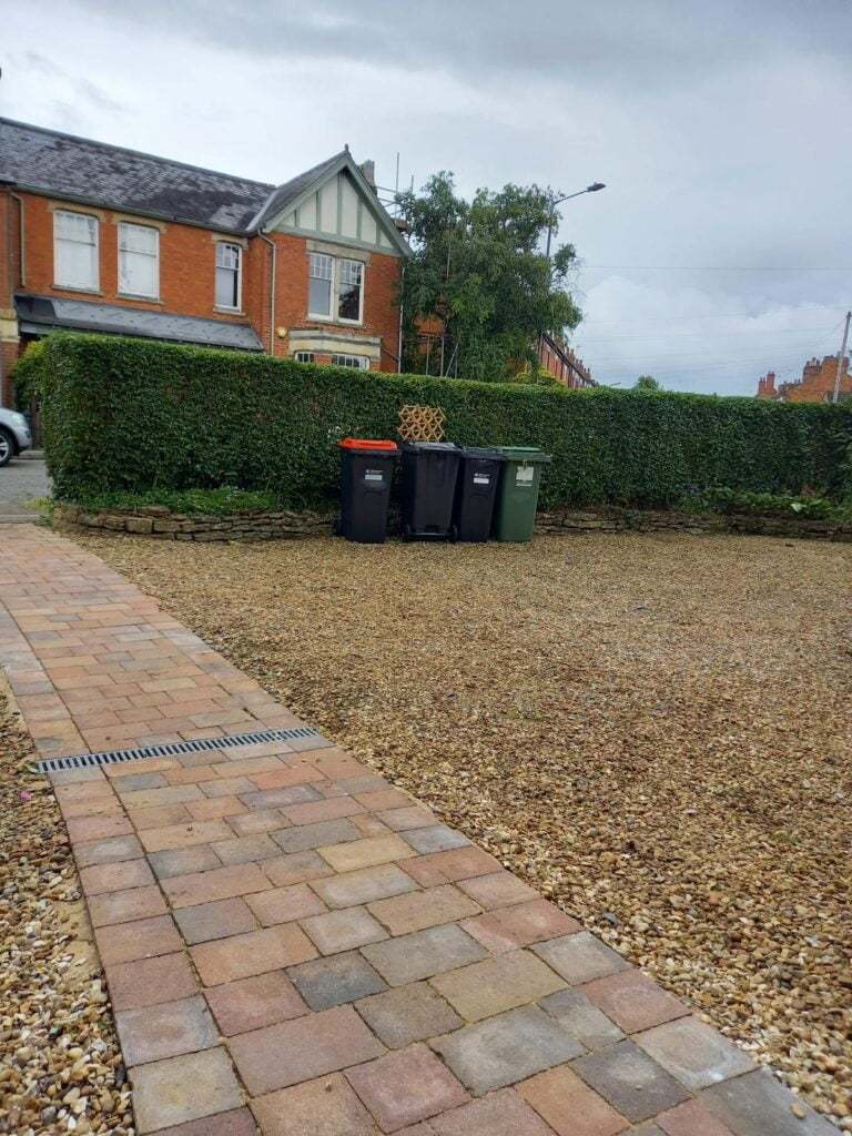 Brick house, bins, hedge, gravel path.