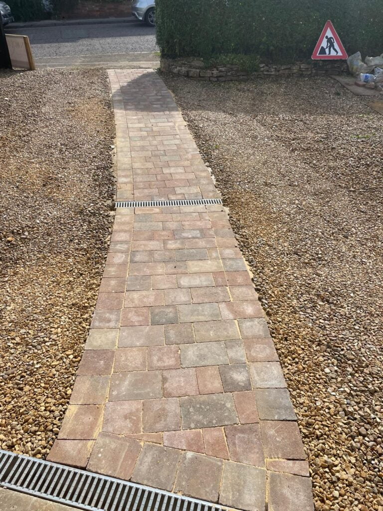 Brick path through gravel with construction sign.