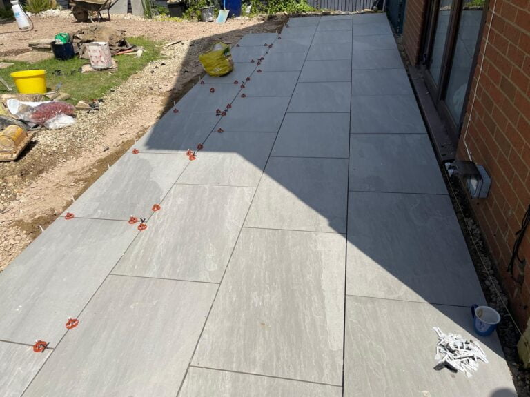 Outdoor patio under construction with grey tiles.